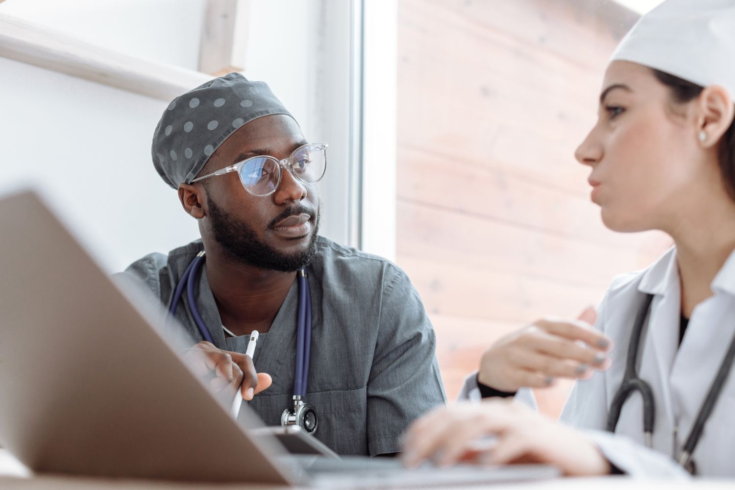 Fotografia ilustrativa de dois profissionais de saúde conversando diante de um notebook